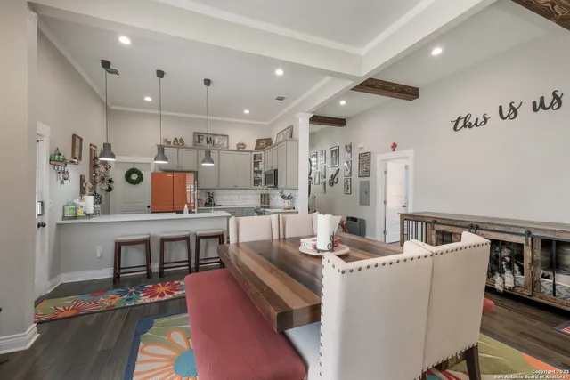 a room with stainless steel appliances kitchen island granite countertop a dining table chairs and a refrigerator