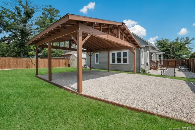 a yellow house with a small yard and a large tree