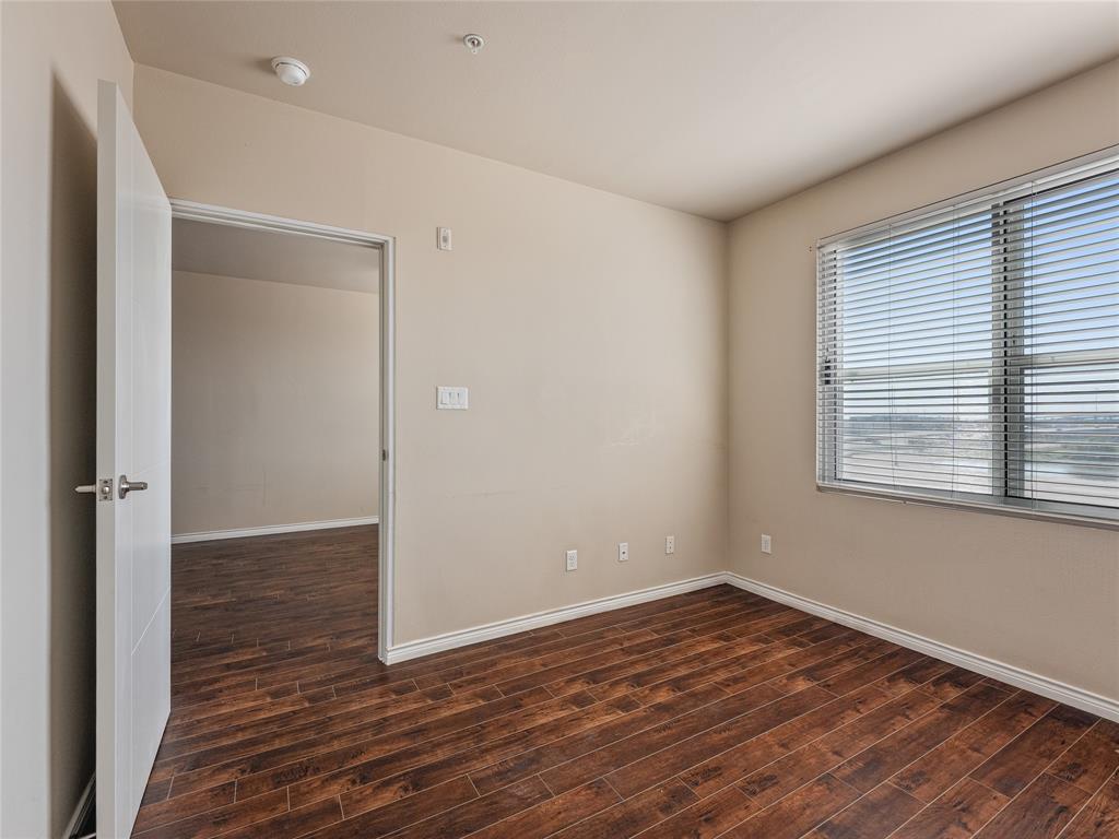 1100 West Trinity Mills Road, Unit 3032 Carrollton, TX 75006 - Photo 13 of 31 a view of an empty room with wooden floor and a window