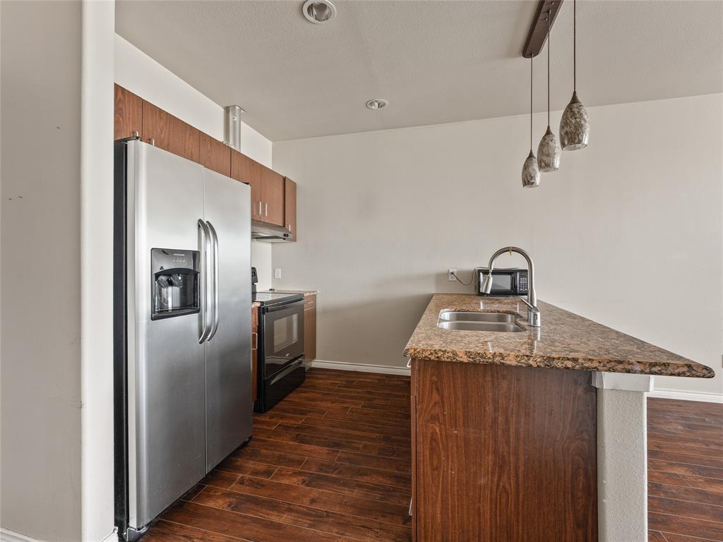 1100 West Trinity Mills Road, Unit 3032 Carrollton, TX 75006 - Photo 2 of 31 a kitchen with kitchen island a sink appliances and wooden floor