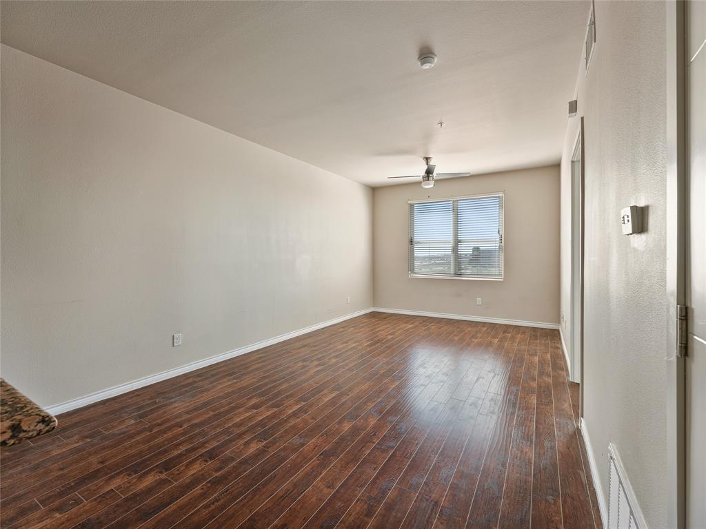 1100 West Trinity Mills Road, Unit 3032 Carrollton, TX 75006 - Photo 4 of 31 an empty room with wooden floor and windows