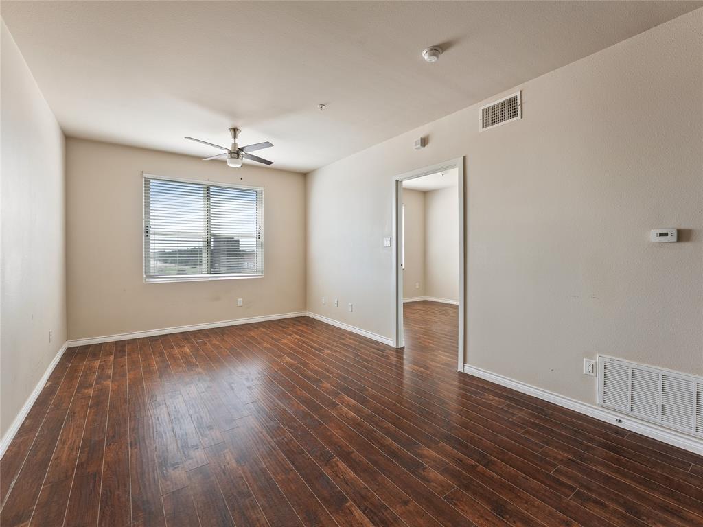 1100 West Trinity Mills Road, Unit 3032 Carrollton, TX 75006 - Photo 5 of 31 an empty room with wooden floor chandelier and windows