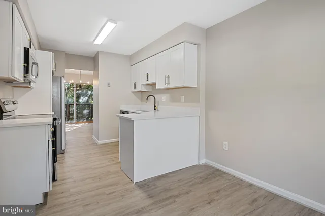 a kitchen with a sink a window a refrigerator and white cabinets