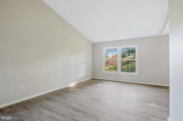 an empty room with wooden floor and window
