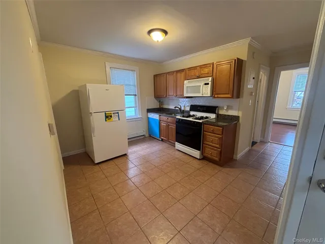 a kitchen with stainless steel appliances a stove a microwave a sink a refrigerator white cabinets and wooden floor