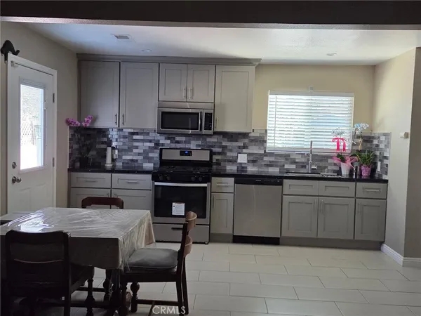 a kitchen with stainless steel appliances granite countertop a stove a sink a microwave a dining table and chairs