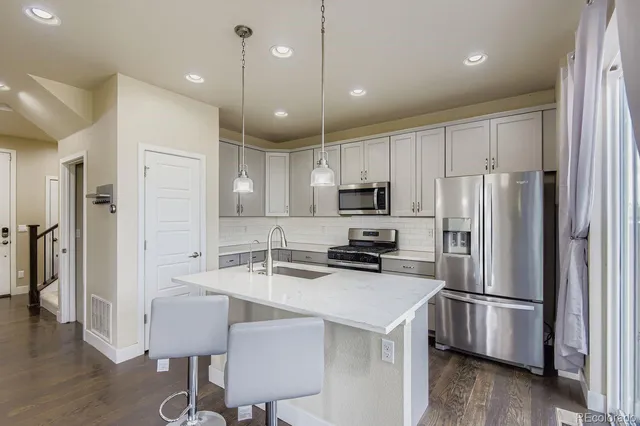 a kitchen with a refrigerator a stove a sink and a dining table with wooden floor