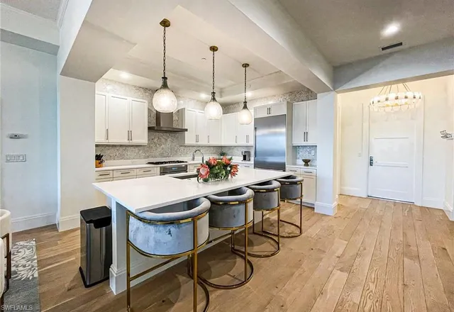 a open kitchen with stainless steel appliances granite countertop a stove a sink dishwasher and a dining table with wooden floor