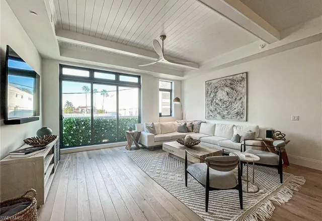 a living room with furniture floor to ceiling window and wooden floor
