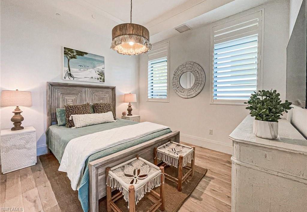 875 6th Avenue South, Unit 204 Naples, FL 34102 - Photo 18 of 29 a bedroom with a bed and a chandelier