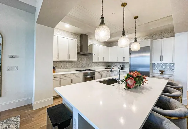 a kitchen with stainless steel appliances a stove a sink a dining table and chairs with wooden floor