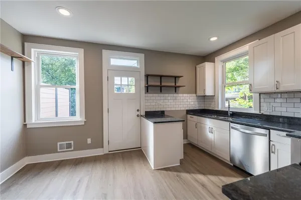 a kitchen with stainless steel appliances granite countertop a stove a sink and a microwave