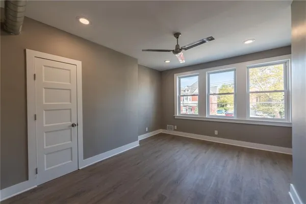 an empty room with wooden floor and windows