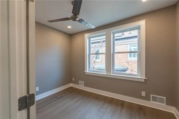 an empty room with wooden floor cabinet and windows