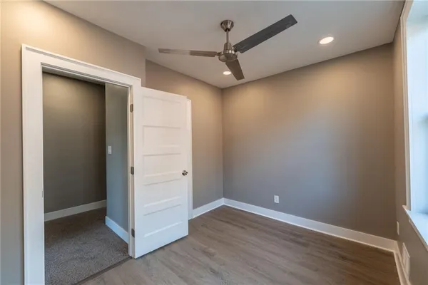 an empty room with wooden floor and a ceiling fan