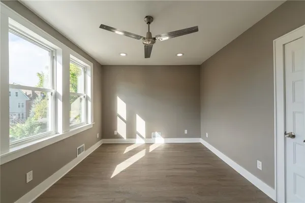 an empty room with wooden floor and windows