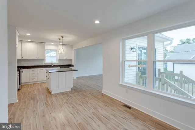 a large kitchen with kitchen island white cabinets and wooden floor