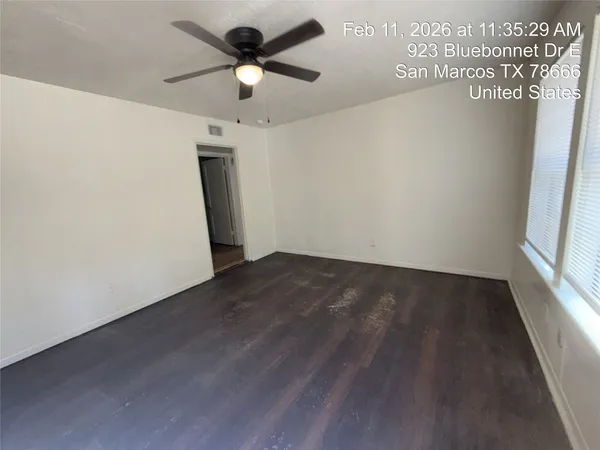 en empty room with wooden floor ceiling fan and window