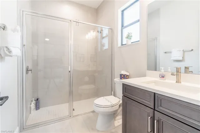 a bathroom with a shower sink vanity mirror and toilet