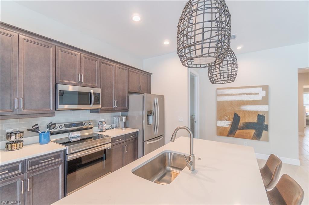 822 105th Avenue North Naples, FL 34108 - Photo 8 of 30 a kitchen with stainless steel appliances a sink dishwasher a stove a microwave oven with cabinets and wooden floor