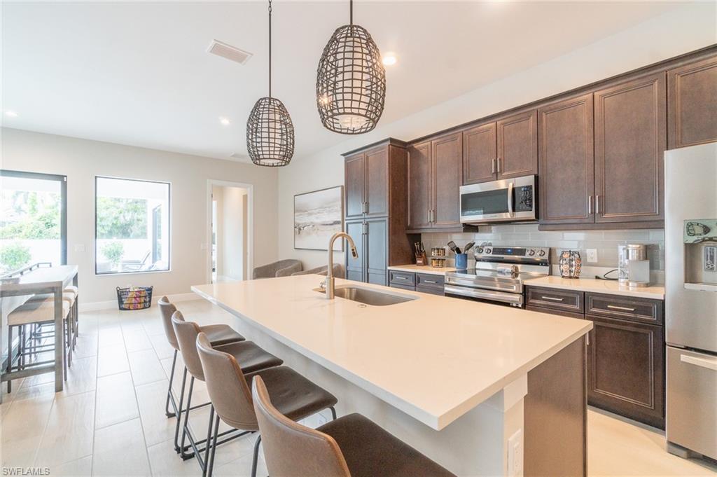 822 105th Avenue North Naples, FL 34108 - Photo 9 of 30 a kitchen with stainless steel appliances granite countertop a sink a stove a table and chairs