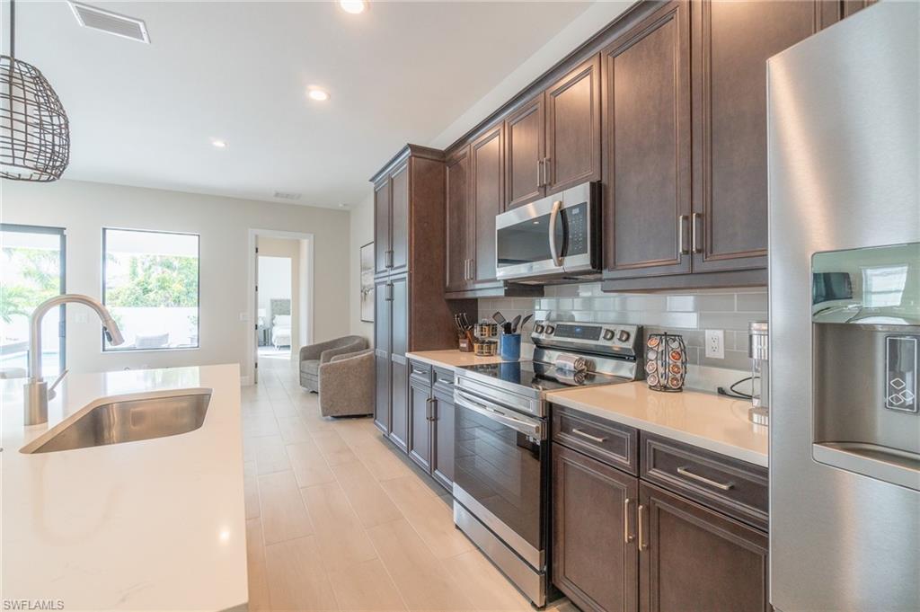 822 105th Avenue North Naples, FL 34108 - Photo 10 of 30 a kitchen with stainless steel appliances granite countertop a sink stove and refrigerator