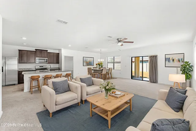 a living room with furniture kitchen view and a window