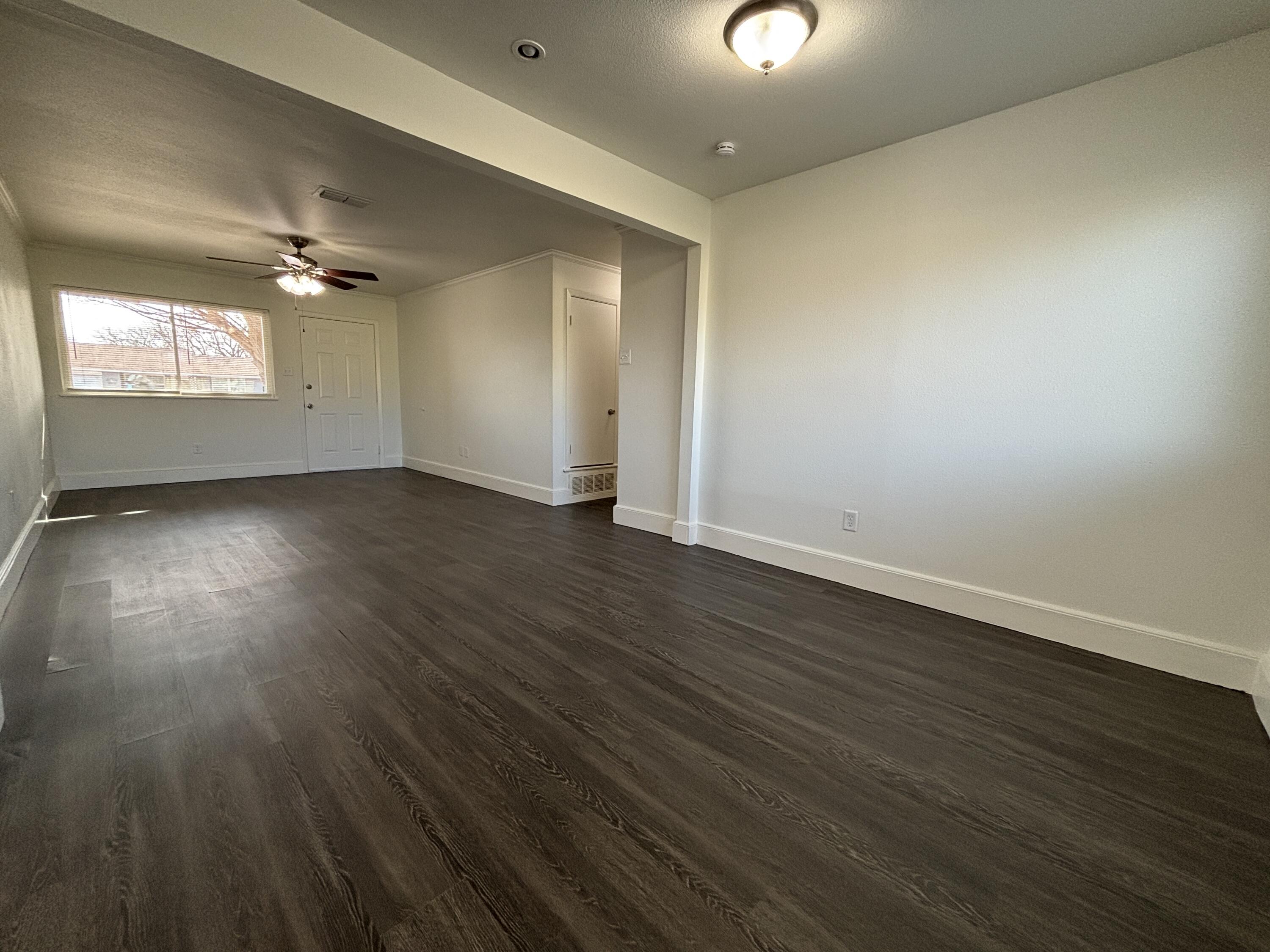 7406 Globe Avenue Lubbock, TX 79404 - Photo 4 of 10 an empty room with wooden floor ceiling fan and windows