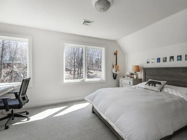 a bedroom with a bed a desk and chair with window