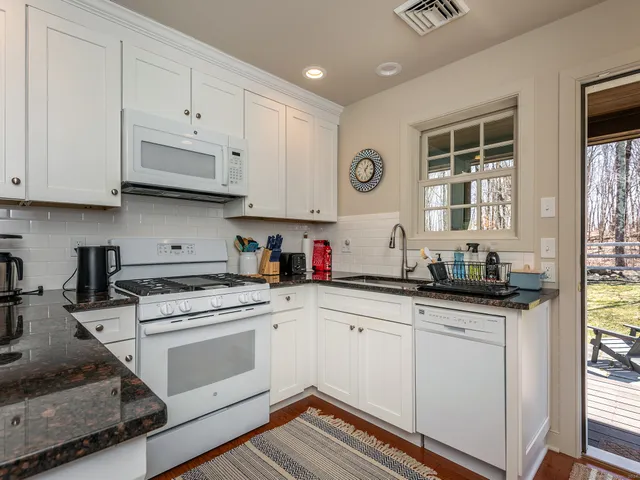a kitchen with granite countertop white cabinets and white appliances