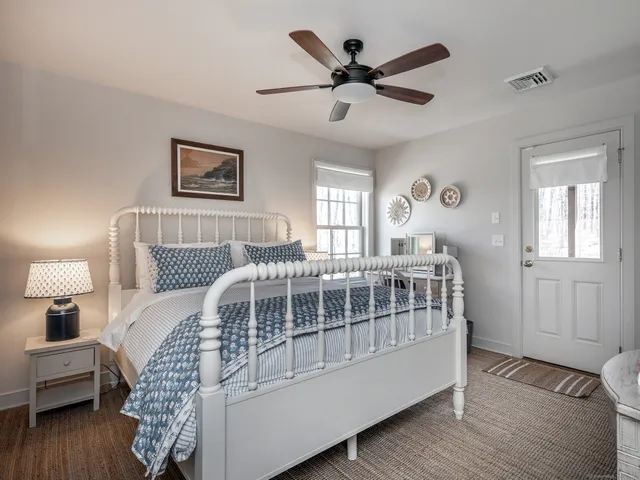 a bedroom with a bed next to a window with a workspace
