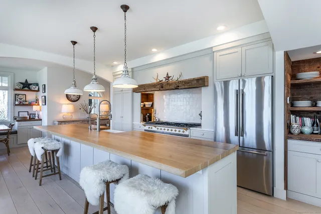 a large kitchen with kitchen island a large counter top space a sink stainless steel appliances and cabinets