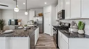 a kitchen with granite countertop a sink a counter top space stainless steel appliances and cabinets