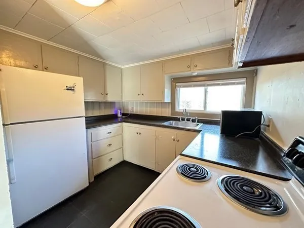 a kitchen with a refrigerator a stove a sink and white cabinets