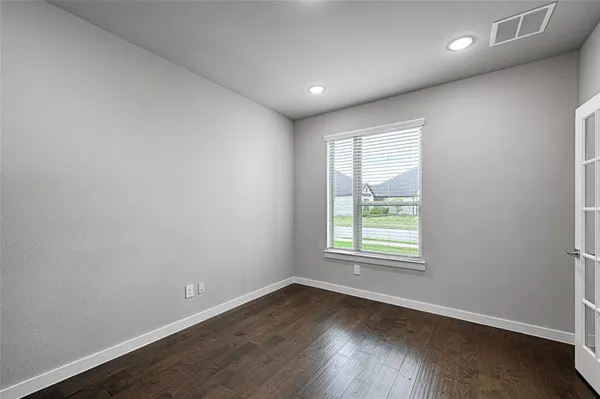 an empty room with wooden floor and windows