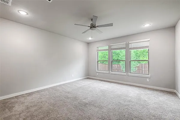 an empty room with a ceiling fan and windows