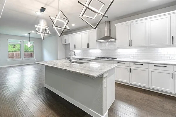 a kitchen with kitchen island granite countertop a sink cabinets and wooden floor