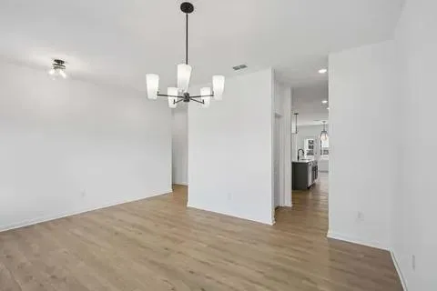 a view of an empty room with wooden floor a fireplace and a window