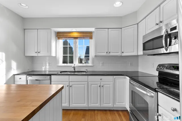 a kitchen with stainless steel appliances granite countertop a sink and cabinets with wooden floor