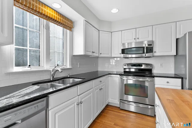 a kitchen with stainless steel appliances granite countertop a sink and a stove