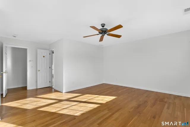 a view of a big room with wooden floor and a ceiling fan