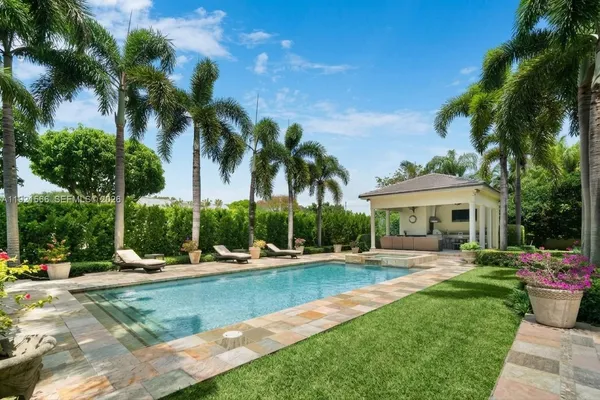a view of a swimming pool with a table and chairs under palm trees