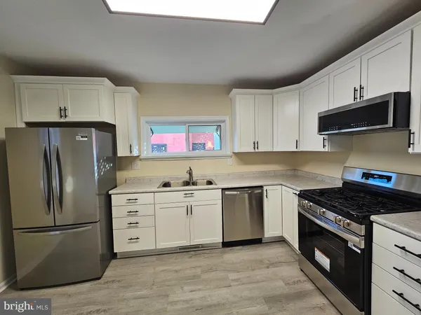a kitchen with stainless steel appliances a stove a sink a refrigerator and cabinets