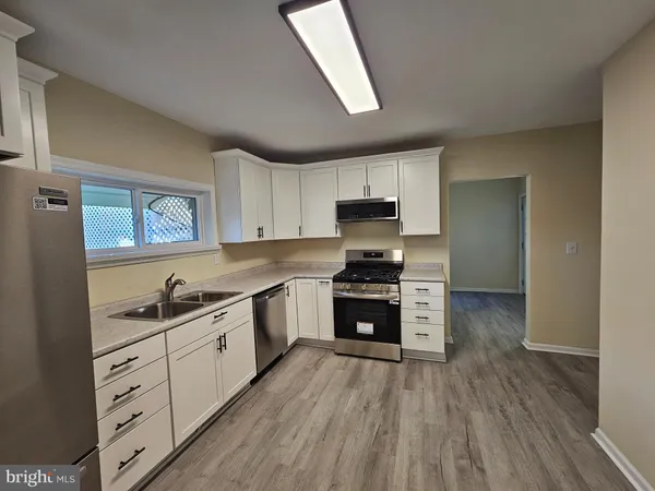 a kitchen with kitchen island granite countertop a sink cabinets and stainless steel appliances