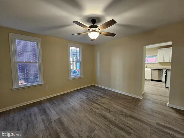 a view of an empty room with window and wooden floor