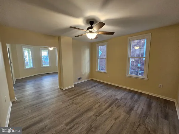 a view of an empty room with window and wooden floor