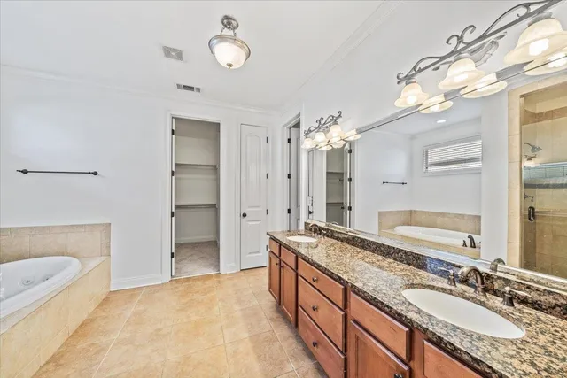 a spacious bathroom with a granite countertop double vanity sink a mirror and a bathtub