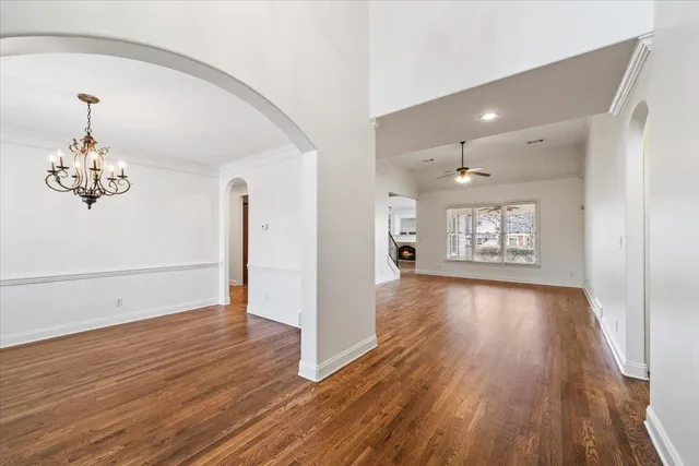 an empty room with wooden floor chandelier and windows