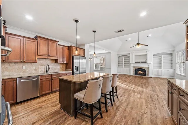 a kitchen with stainless steel appliances granite countertop a kitchen island hardwood floor sink stove dining table and chairs