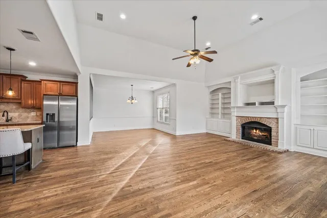 a view of an empty room with a fireplace and a chandelier fan